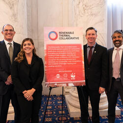 Four people stand with a "Renewable Thermal Collaborative" sign