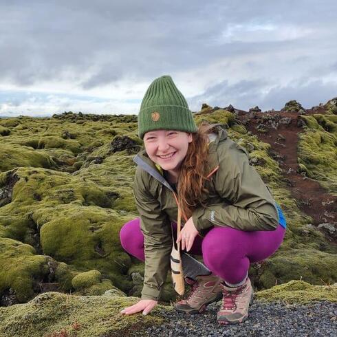 Rachel Golden Kroner crouches before a mossy landscape