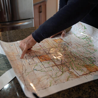 A rancher points at a map sitting on a countertop