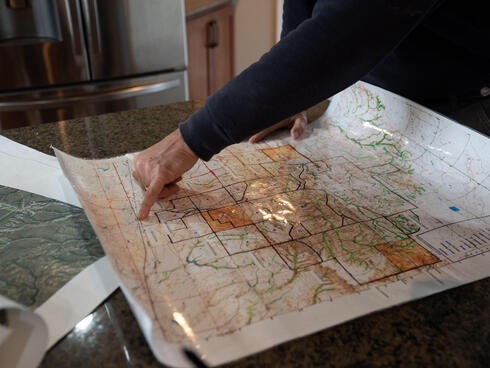A rancher points at a map sitting on a countertop