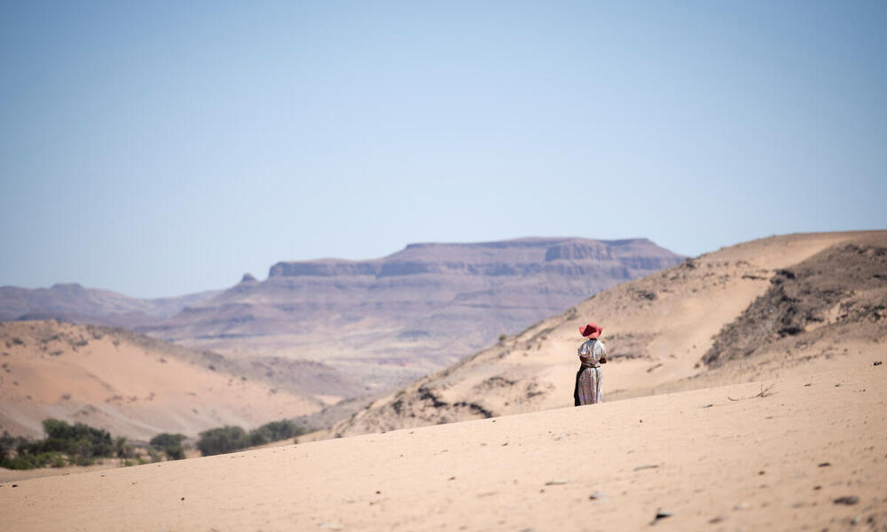 Rebecca Adams, a goat herder, stands in the stark landscape outside De Riet village, Namibia