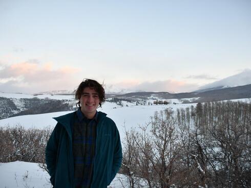 Young man standing in front of a field with snow