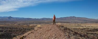 Amy Erickson stands on a tall rock overlooking the Rio Grance Basin