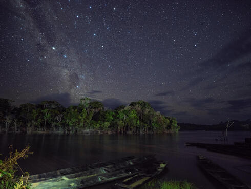 Nightime view of sky, trees, and boats along the River Igara Paraná