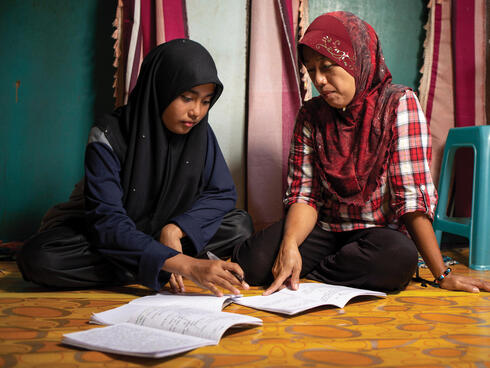 Girls in headscarves work on studies