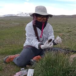 Sabita Gurung sits in a field holding a sample