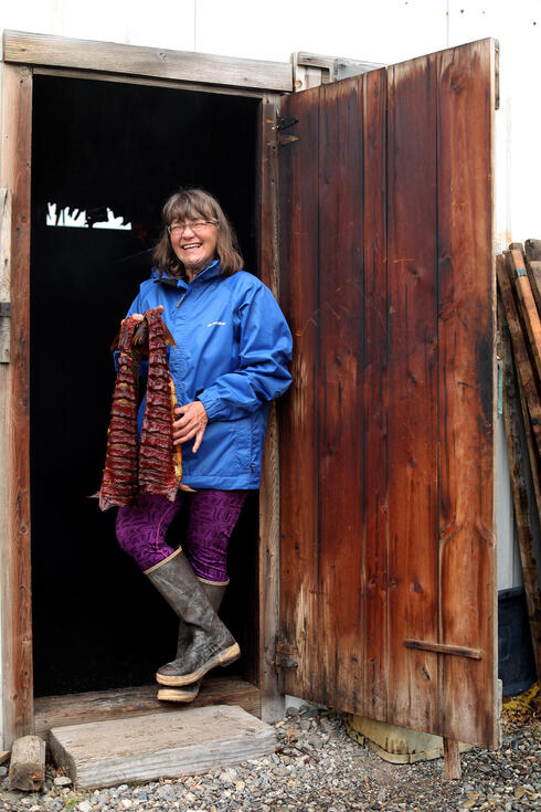 Carolann Hester standing in door holding salmon