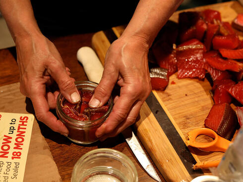 Closeup of person packing salmon in jar