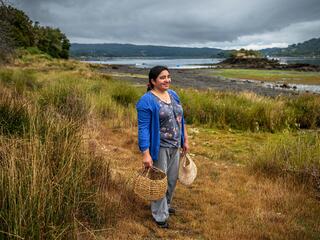 Sandra Antipani stands on a waterfront walking path near the ecotourism cabins she manages
