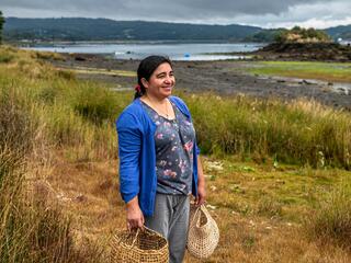 Sandra Antipani stands on a waterfront walking path near the ecotourism cabins she manages