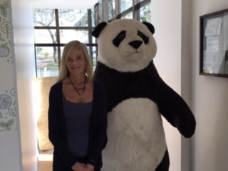 Sheila Bonini stands next to a giant panda costume.