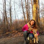 A women poses with her dog in the woods