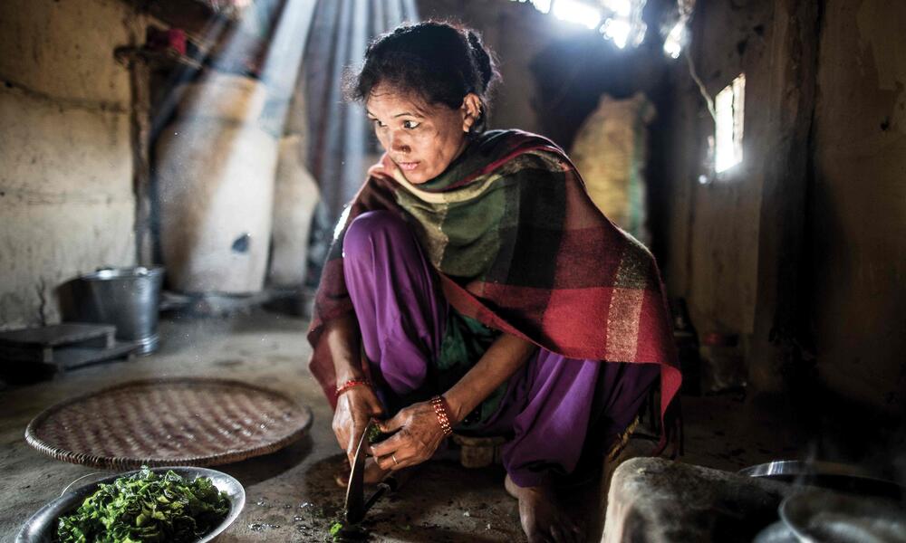 Devi prepares rice, lentils and spinach for her husband and son. The family will eat from this meal for much of the day.
