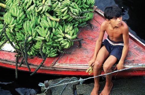 Boy in a boat with bananas