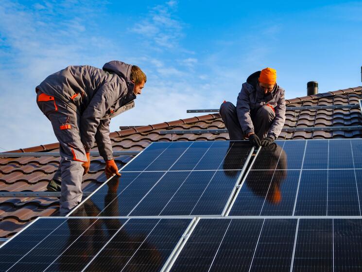 two people installing solar panels on a roof
