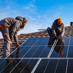 two people installing solar panels on a roof