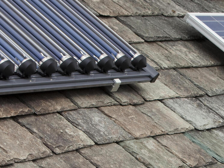 Solar voltaic electricity generating panels and solar hot water panels on a house roof in Ambleside, Cumbria, UK.