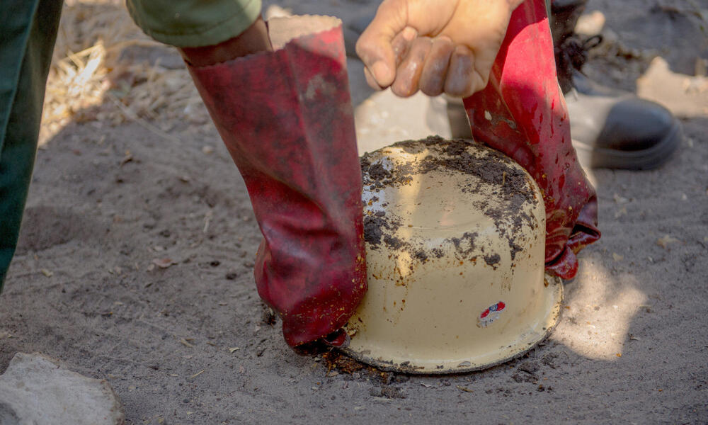 Using a small pot, Mulanda molds the mixture into a cake.