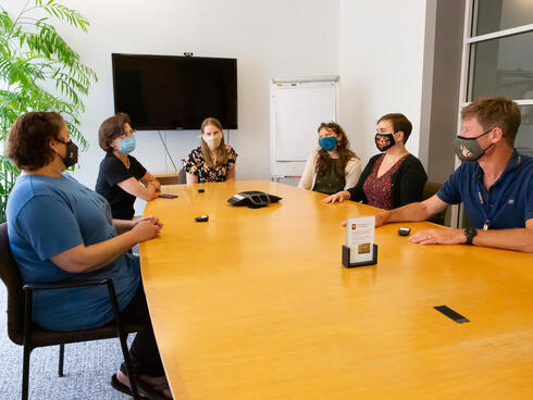 Group of WWF-US staff sitting around a conference table with masks at headquarters.