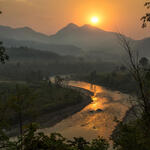 A lush landscape in Nepal with mountains in the background and a winding river at sunrise