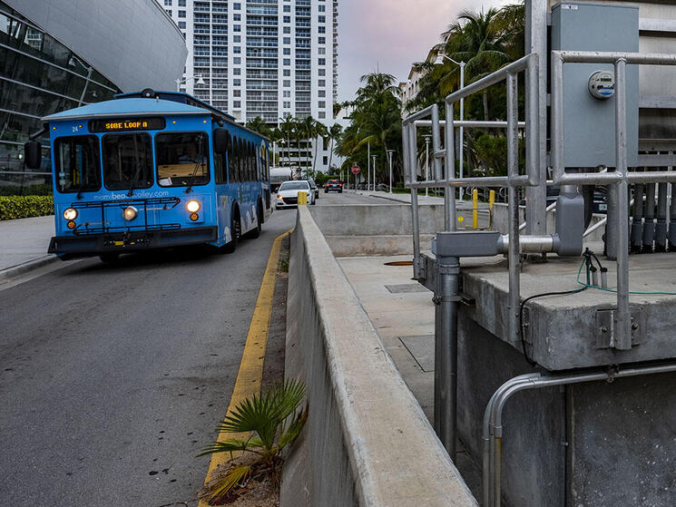 A blue bus on the South Beach Line passes a pump station