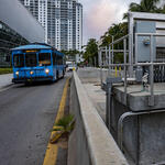 A blue bus on the South Beach Line passes a pump station