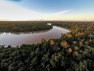 A river winds amid dense forest as the sun sets