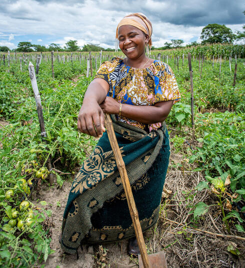 Woman smiles and leans on hoe in field