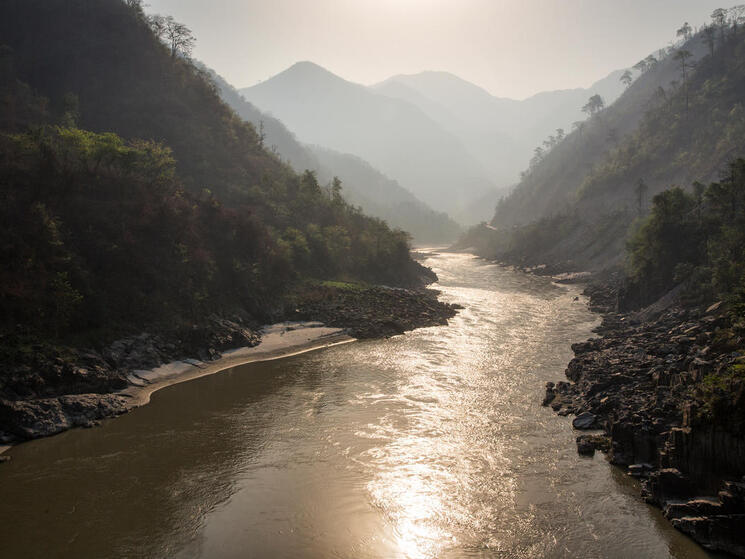 View of a river from ground level in a deep valley surrounded by mountains