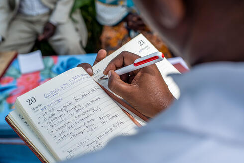 Close up of a person's hand writing notes in a notebook outside