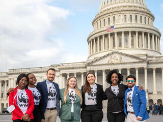 A group of people in WWF shirts stand in a line in front of the US Capitol Building