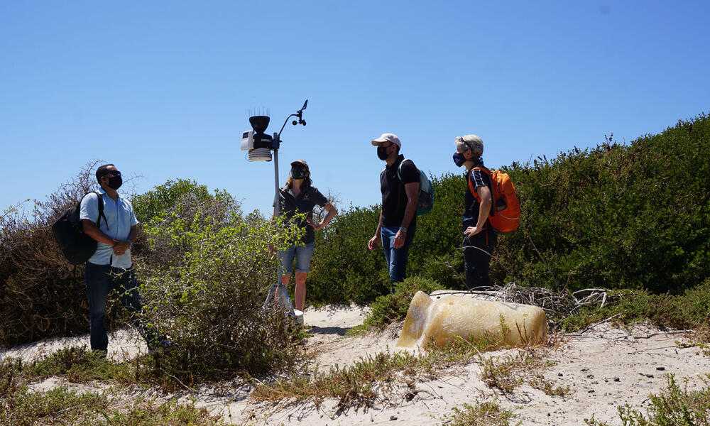 A group views a weather station on a sandy dune in South Africa
