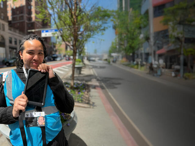 A woman in a WWF lanyard stands on a sidewalk and holds a tablet