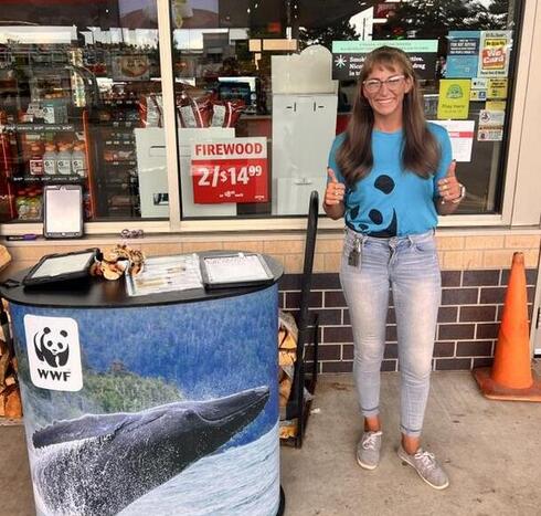 A woman with thumbs up standing at kiosk outside store