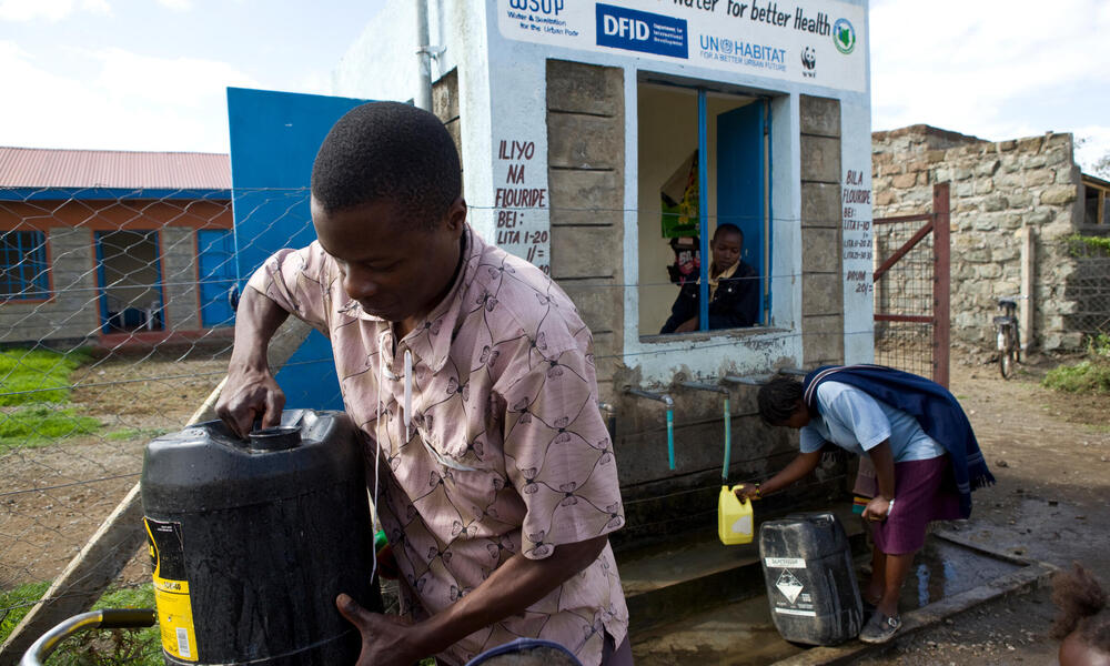 A young man collects water from a water kiosk in Kenya