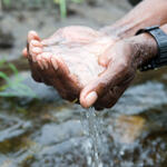 Close-up of cupped hands holding water over a stream