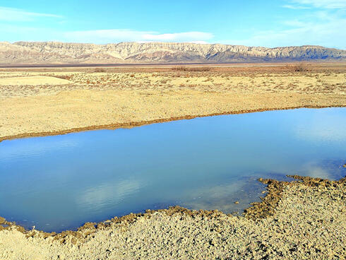 Aerial photo of large watering hole in barren landscape