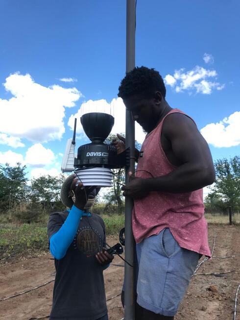 Two men install an automated weather station