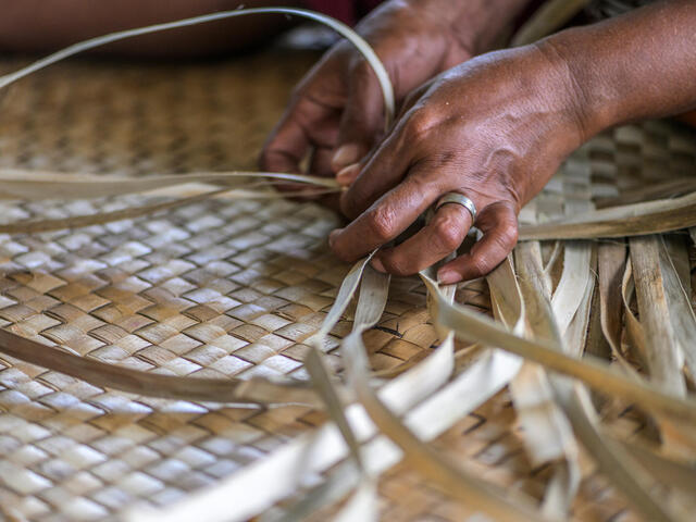 Closeup of hands weaving dry grass mats