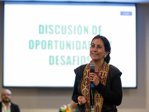 A woman stands in front of display with microphone