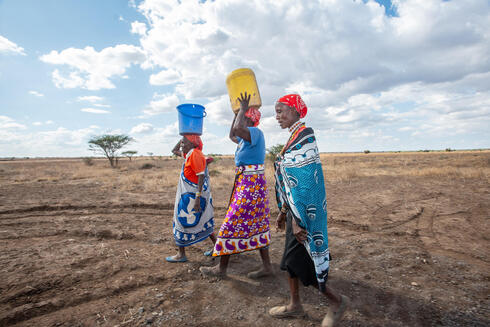 Women walking in a field with buckets on heads