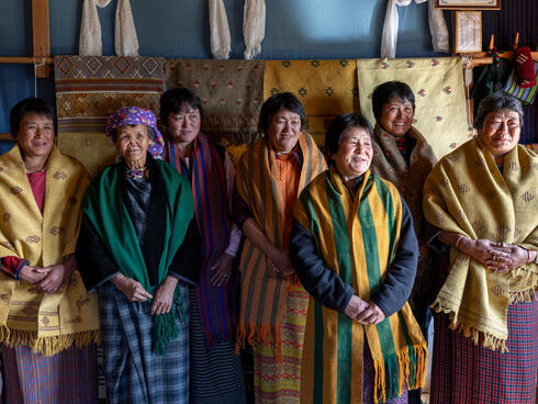 A group of smiling women wearing colorful woven cloth