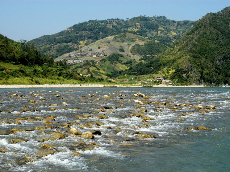 water flowing over rocks with mountains in the background