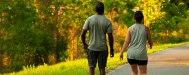 Man and woman walking on a hiking trail on a sunny day with 