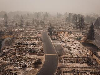 Aerial view of a neighborhood scorched by wildfire with only foundations left of houses