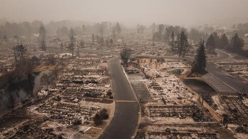 Aerial view of a neighborhood scorched by wildfire with only foundations left of houses