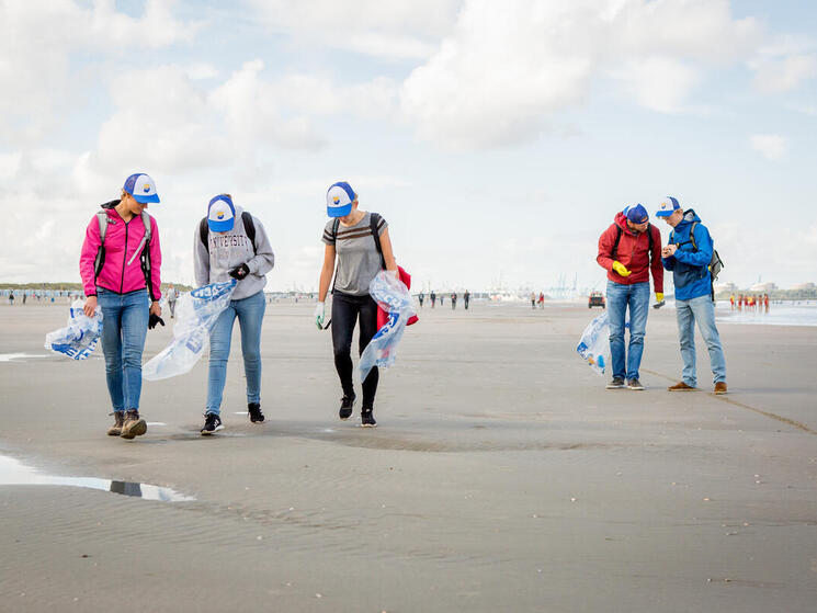 people picking up trash on a beach