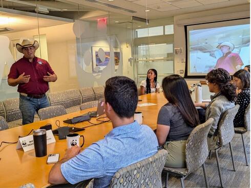A group of BRIDGE interns sit and talk together in a conference room at WWF-US Headquarters in Washington, DC