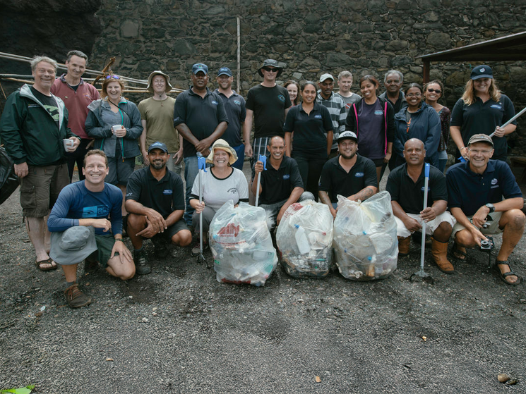 A group of people posing for the camera with bags of trash they've collected