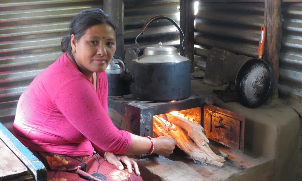 A woman cooking with a metallic improved cook stove.